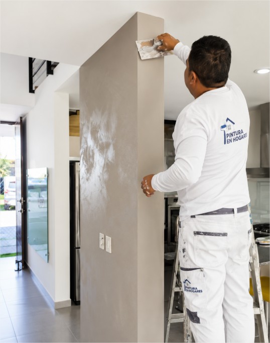 Pintor preparando una pared antes de aplicar pintura